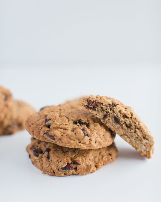 Stack of three cranberry oatmeal cookies with the top cookie broken in half to show the interior.